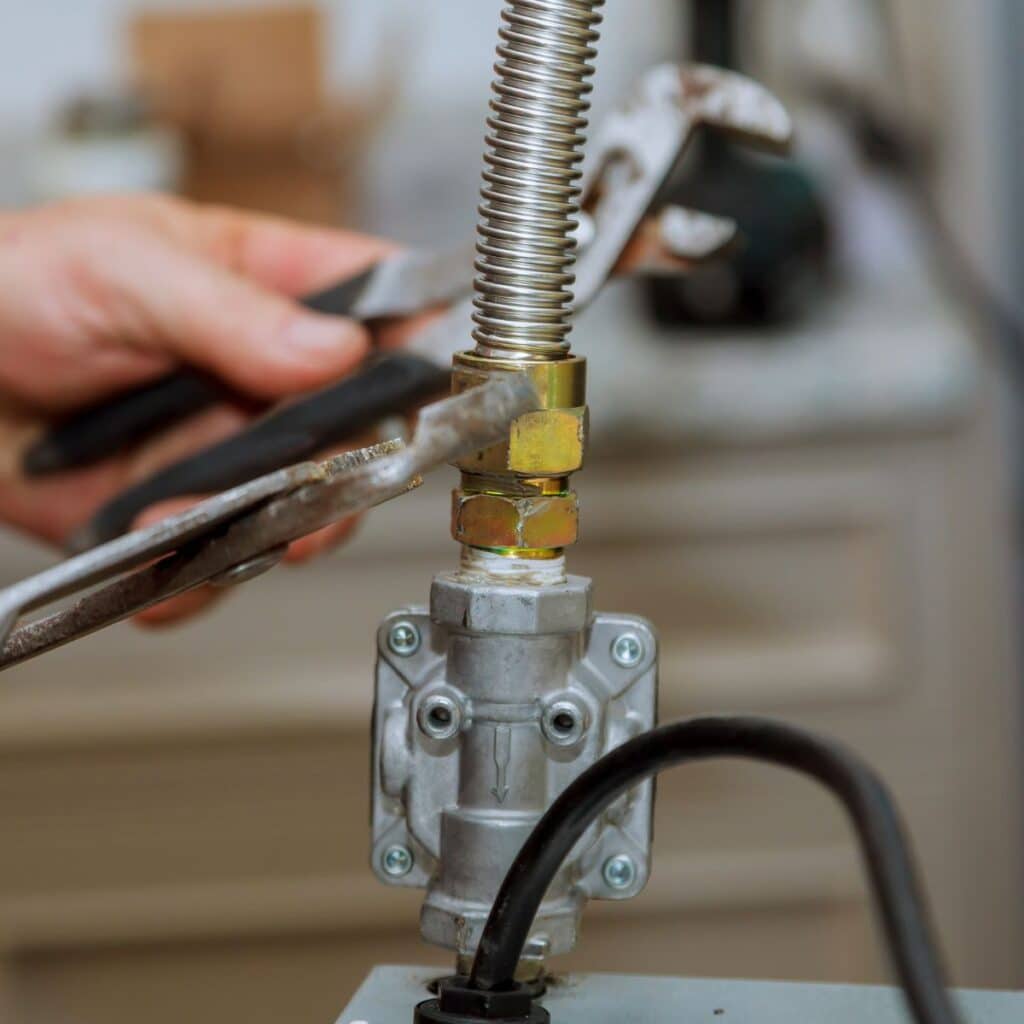 gas line plumber using a pipe wrench to tighten a gas line