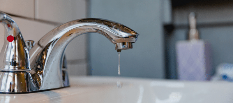 closeup of a water faucet with water dripping out of it